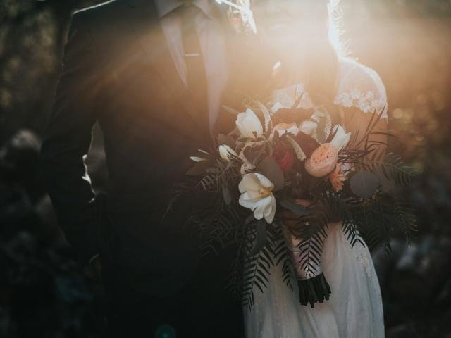 A couple holding a wedding bouquet at golden hour