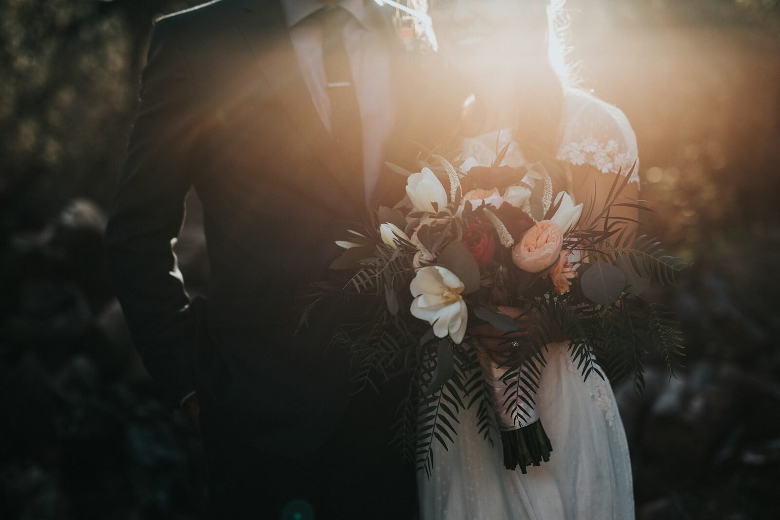 A couple holding a wedding bouquet at golden hour